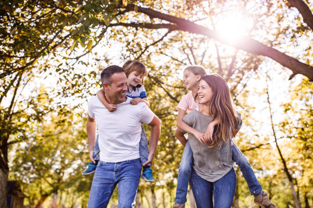 istock Carefree parents and their small kids having fun while piggybacking in springtime. 1448987156