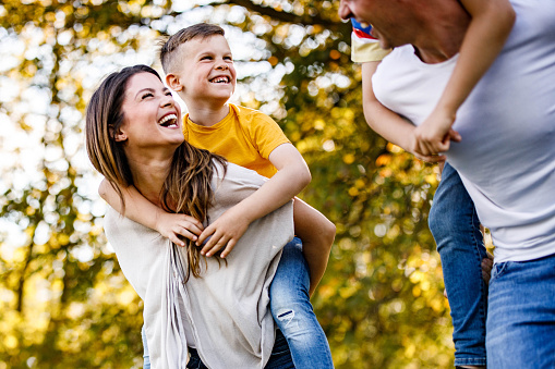 Young happy family having fun while piggybacking in spring day.