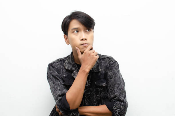 istock A thoughtful, perplexed Asian man considers whether to select something isolated against a white background. man feeling uncertain and unsure. 1448987949