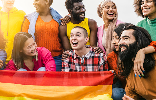 Group of multiracial people enjoy vacation outdoor - Different friends students celebrating gay pride day with rainbow flag -