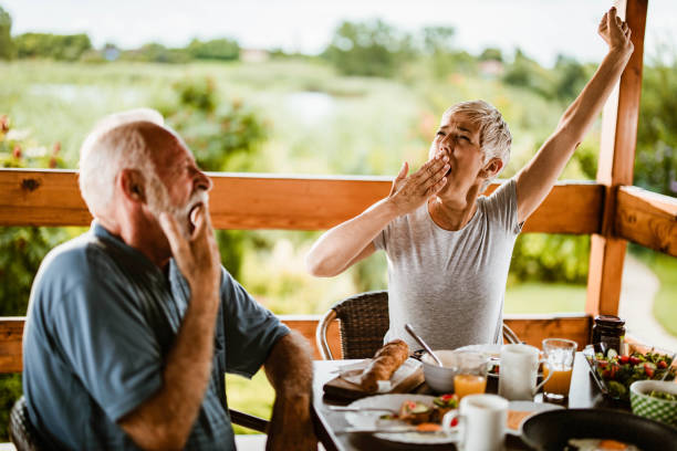 istock Senior couple yawning during breakfast time on a terrace. 1448990174