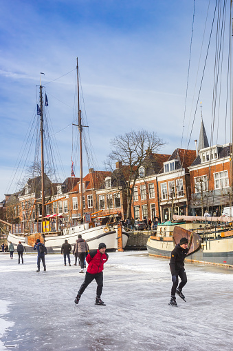 People skating on the canal with historic ships in Dokkum, Netherlands