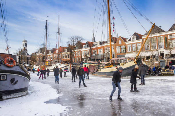 People skating on the canal with historic ships in Dokkum stock photo