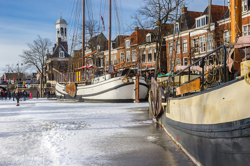 Historic wooden sailing ships and town hall in winter in Dokkum, Netherlands