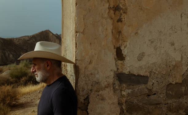 ritratto di uomo adulto in cappello da cowboy in piedi contro il muro nel deserto. almeria, spagna - the western wall foto e immagini stock