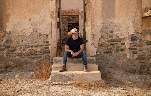 Adult man in cowboy hat and shirt sitting on step