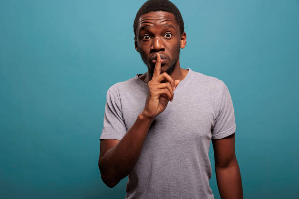 istock Male model doing hush sign with finger over lips to keep secret 1448994152