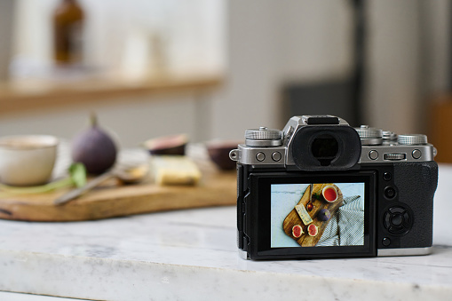 Close-up of professional photo camera on table with still life picture on screen using for photographing professional photos