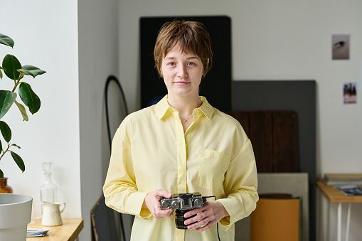 Portrait of professional young photographer looking at camera during shooting in studio