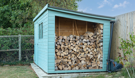 blue Wood shed, large log store filled with cut firewood,