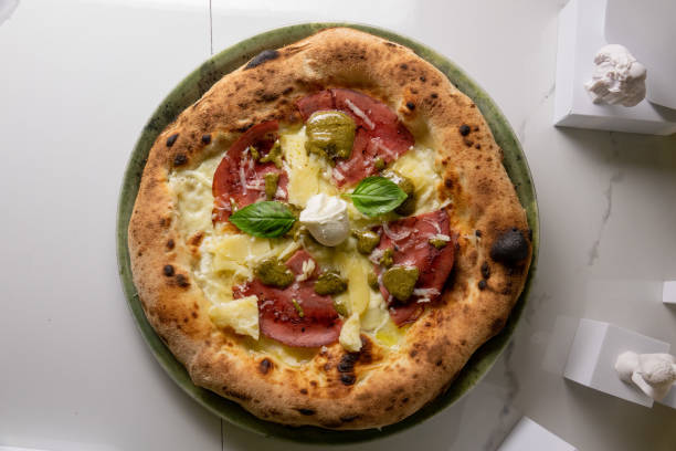 istock Neapolitan pizza cooked ham and mozzarella on the marble table with leaves and statues 1448996343