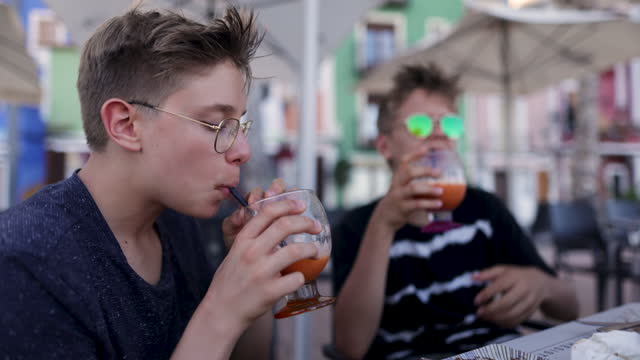 Teenage boys drinking smoothies in a sidewalk café