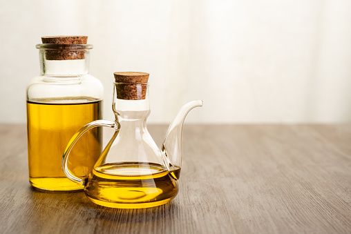 Oil cans with extra virgin olive oil on a counter with a background of a window with lots of light.