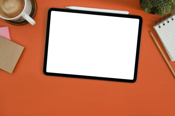 istock Flat lay digital tablet with white empty screen, notepad, coffee cup and potted plant on orange background. 1449007786