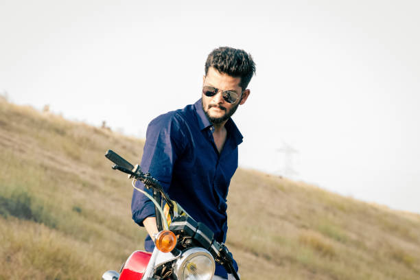Handsome model with beard and sunglasses on motorbike.