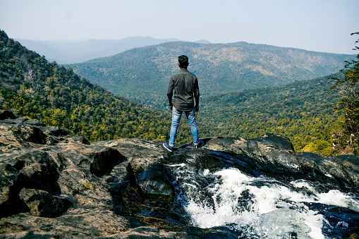 Young Indian hiker standing alone at mountain top enjoying the view.