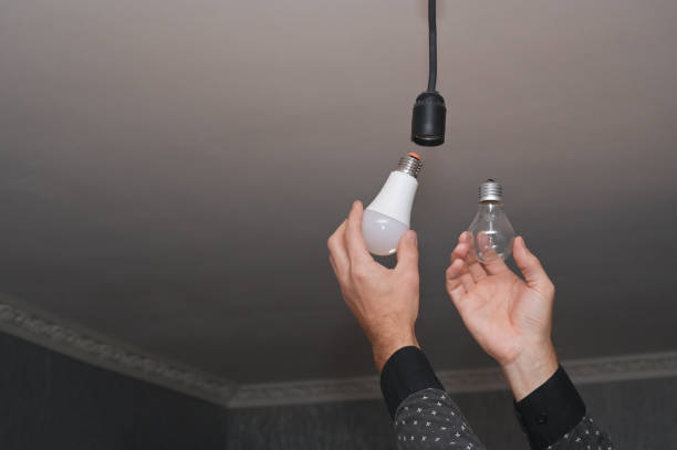 lámpara incandescente y lámpara led de bajo consumo en sus manos. - led lighting equipment light bulb installing fotografías e imágenes de stock
