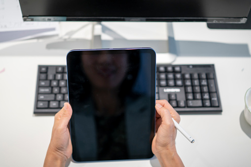 A modern frameless laptop on a table with grass flowers and a mouse - blank screen and soft background