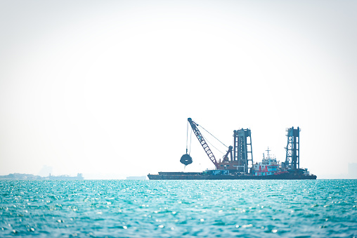 The dredger is dredging out the sea for the ship to pass