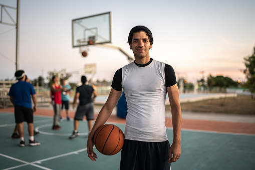 Portrait of young man with sports ball at basketball court