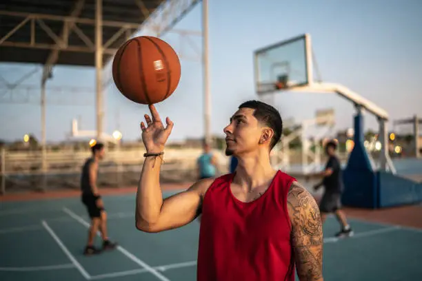 Photo of Young man spinning a basketball ball at a field