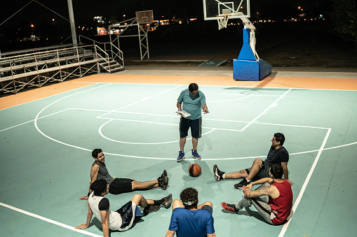 Coach giving instructions to basketball players sports court
