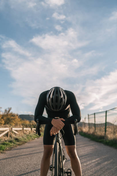 istock Vertical image of a male cyclist dressed in black leaning on his handlebar resting. 1449027737
