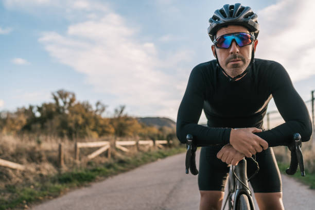 istock Male cyclist dressed in black leaning on his handlebar resting and looking seriously at the camera. 1449027840