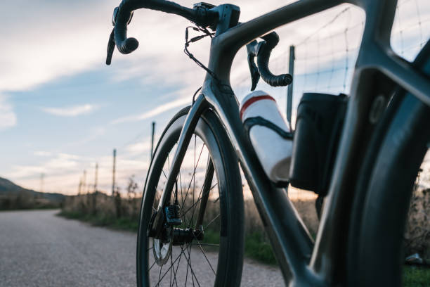 silhouette eines dunklen rennrads auf dem asphalt bei sonnenuntergang. - fahrradrahmen stock-fotos und bilder