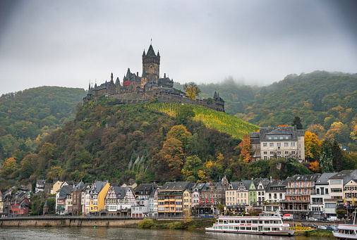 Autumn cityscape with Moselle river, colorful houses on embankment and Cochem Castle