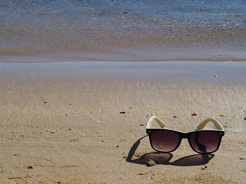 Sunglasses on a sandy beach. Copy space. Сoncept of summer vacation at sea.