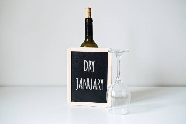 dry january. alcohol-free challenge, health campaign urging people to abstain from alcohol for the january month. bottle of wine, glass and sign with text dry january - dry january stockfoto's en -beelden