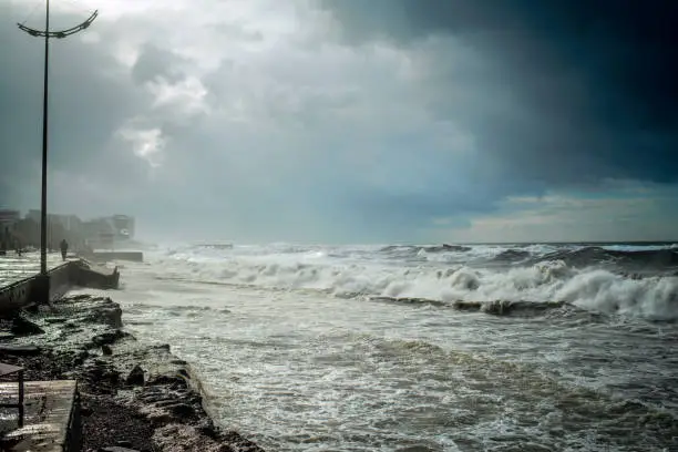 Photo of Sea waves crashing over destroyed road and coastline during stormy extreme weather