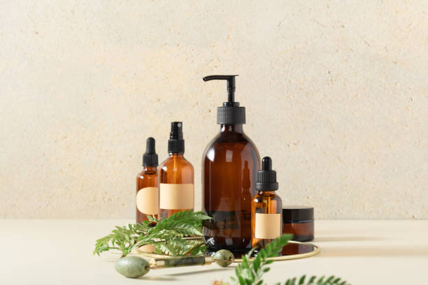 Amber glass bottles on beige background. Soap liquid, shampoo or shower gel, serum, essential oils, anti-age products packaging design stock photo