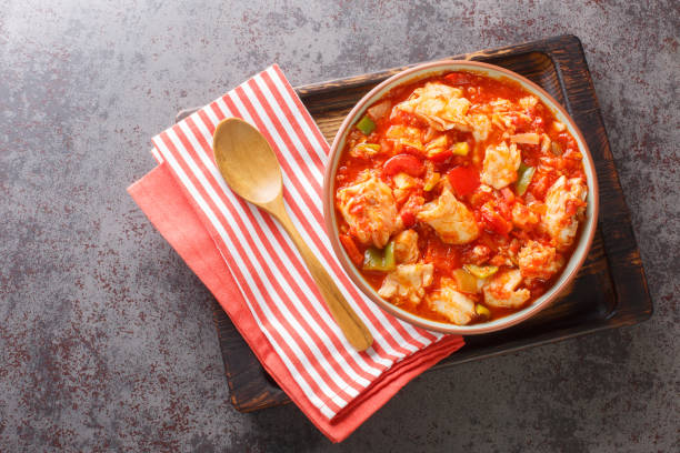 istock Cod stew with vegetables peppers, tomatoes, garlic and onions close-up in a bowl. Horizontal top view 1449034093