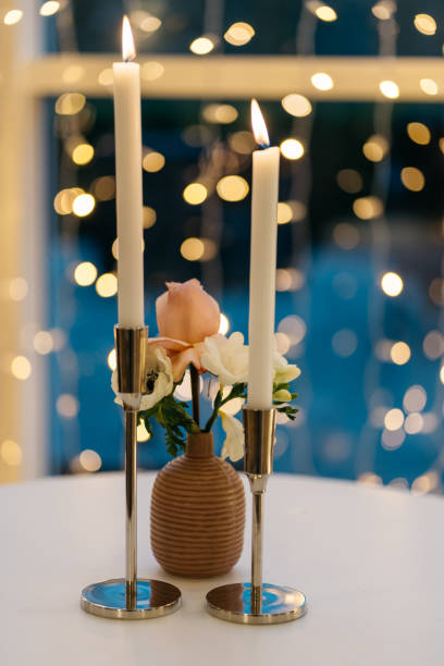 istock two burning candles and flower vase with light dots in background 1449034917