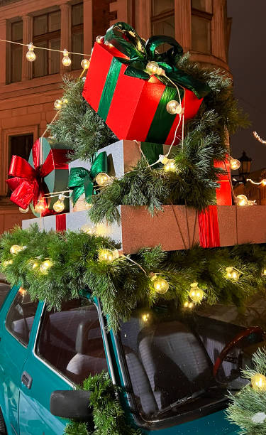 istock Santa's old vintage car with gift boxes on top. Closeup branches of coniferous tree decorated shiny light garland. Perfect festive content for stories background, vertical banner. 1449036023