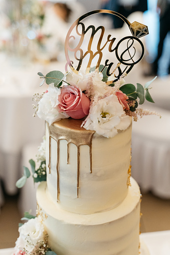 Beautiful big wedding cake with three storey decorated by tender sweet roses. White wedding cake with three levels and white roses