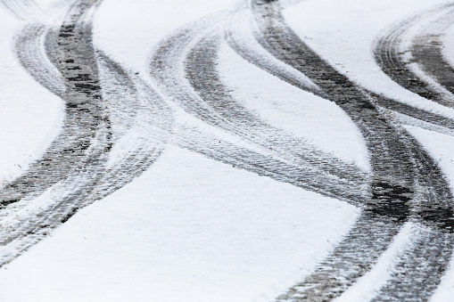 Close up image depicting car tyre tracks in the winter snow.