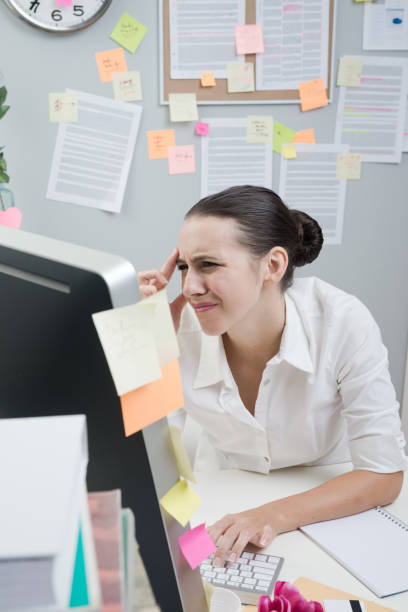 Tired female white collar working at computer with eye pain touching her temples.