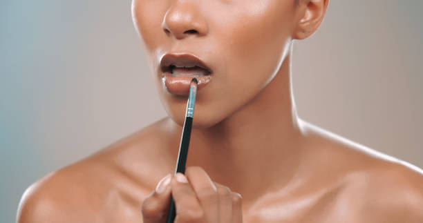 istock Studio shot of female model applying lipstick with brush 1449041987