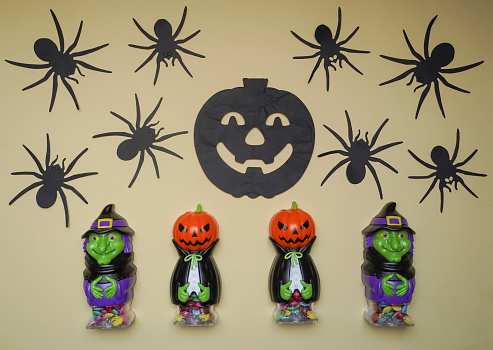 Cute characters in monster costume. Scary Halloween figurines stand on a light background close-up, behind hangs terrible black pumpkin. Halloween concept. Holiday decorations
