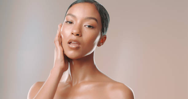 Studio shot of beautiful woman touching her glowing face