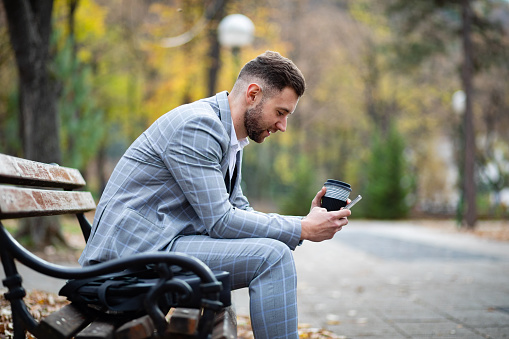 Elegantly dressed businessman reading on a tablet outdoors