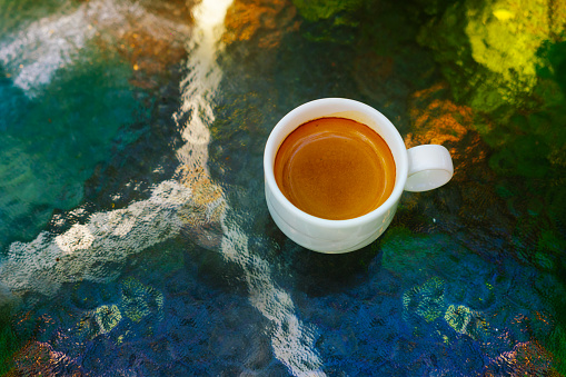 espresso coffee In white glass placed on a multicolored glass table