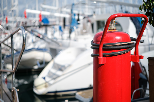 Fire extinguisher close-up on the mooring of the yacht club, blurred background. providing fire protection and safety prevention.
