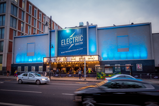 London, UK - People outside the entrance to the Electric Brixton at night as cars pass on the street.