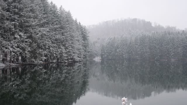 Snow fall mountain lake, water reflection