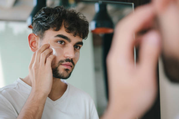 istock Bearded man applying eye patches under his eyes while looking at mirror. Wrinkles and face home care for men. Skin care routine. Home spa care concept. Facial treatment, cosmetology, beauty concept. 1449059455