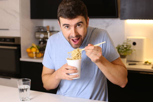 istock Cute guy eating instant noodles 1449062006
